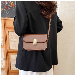 Detail of vintage brown shoulder bag showing golden clasp and glossy leather texture