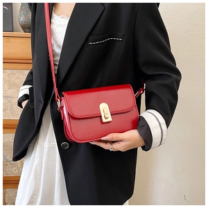 Close-up of vibrant red leather shoulder bag featuring a polished gold metal clasp