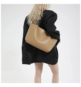 Close-up of large minimalist camel tote bag with black shoulder straps for commute