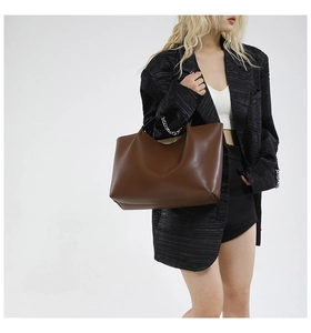 Detail of dark brown leather tote bag with silver chain handles and minimalist finish