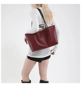 Deep burgundy large tote bag with black slim straps shown from a stylish side angle