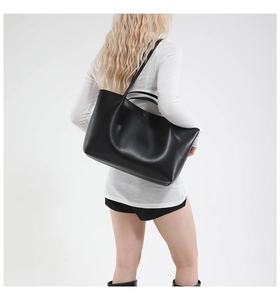 Minimalist large black matte leather tote bag shown on a model for casual commuting