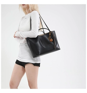 Detailed look at the large black leather tote bag with elegant tassel charm and long straps