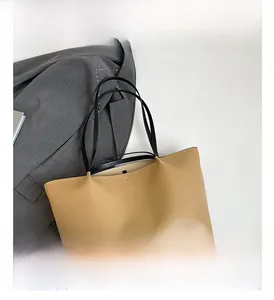 Close-up of matte khaki tote bag featuring slim black handles and spacious design
