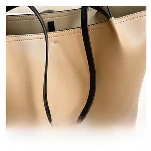 Detail view of the fine stitching and durable strap attachment on the beige tote bag