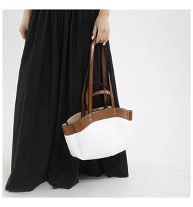 Detail of a brown and white tote bag with wave-cut edges and dual shoulder straps