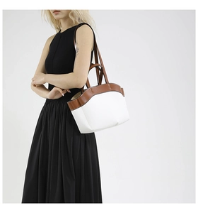 Detail of cream and brown bucket bag worn by model on a minimalist black dress