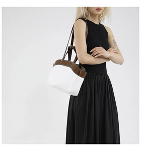 Detail of contrast stitching on white leather tote with brown shoulder strap accents
