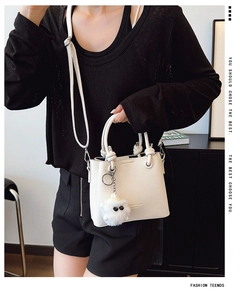 Close-up of white lychee texture bucket bag with woven handle and plush monster charm