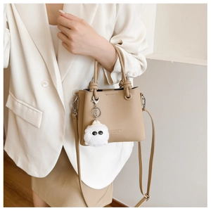 Detail of beige bucket bag with litchi texture and a funny plush eyeball charm