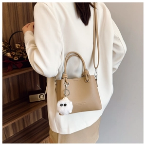 Detail of khaki bucket bag with lychee texture leather and plush monster charm