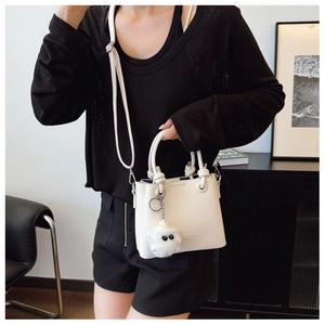 Off-white bucket bag with knotted handles and plush charm shown in a lifestyle setting