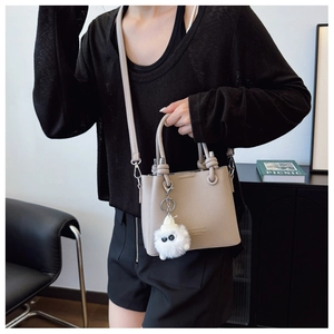 Detail of beige lychee grain bucket bag with knot handle and cute plush charm
