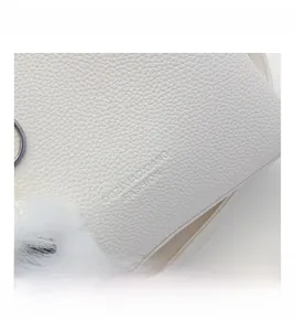 Detail of white lychee pattern leather bucket bag with fuzzy ball charm and logo