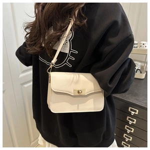 Petit sac carré crème porté par un mannequin dans un décor d'intérieur minimaliste moderne