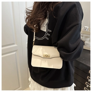 Gros plan sur un sac à bandoulière en cuir crème avec un élégant fermoir doré rotatif