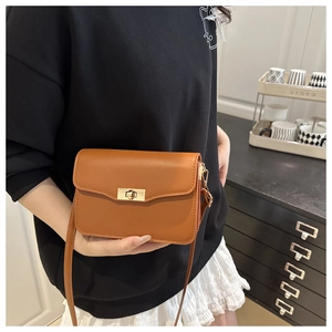 Détail d'un sac bandoulière en cuir caramel avec boucle rectangulaire dorée chic