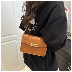 Sac bandoulière carré vintage marron avec boucle en métal doré porté par un modèle