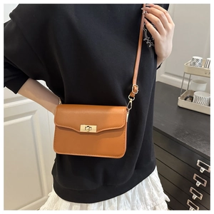 Détail d'un sac à bandoulière carré marron vintage avec fermoir tournant en métal doré