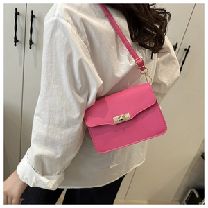 Sac bandoulière rectangulaire rose avec fermoir doré porté par un mannequin en chemise