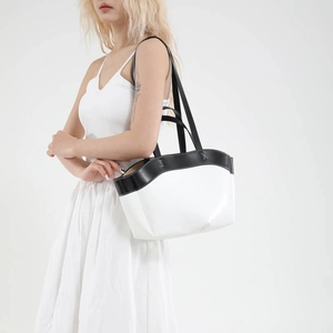 Minimalist black and white contrast leather bucket tote bag shown on model shoulder