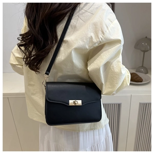 Détail d'un sac à bandoulière en cuir noir avec fermoir doré porté par un mannequin de dos