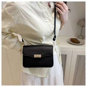 Détail d'un sac bandoulière noir avec fermoir rotatif doré et bandoulière réglable