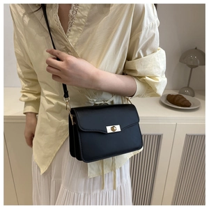 Détail du sac bandoulière en cuir noir mat avec fermoir tournant doré et côtés en accordéon