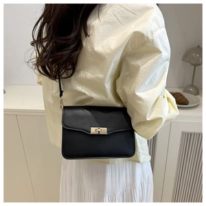 Petit sac rétro en cuir noir mat avec fermoir doré porté à l'épaule par un mannequin