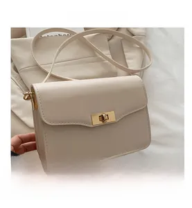 Détail d'un sac à bandoulière en similicuir beige avec fermoir rotatif en métal doré