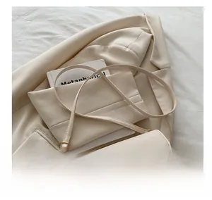 Détail de la bandoulière réglable avec boucle dorée sur un sac bandoulière beige épuré