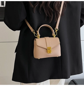 Detail view of beige lychee leather mini bag with gold hardware and top handle strap