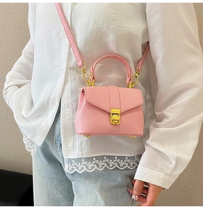 Close-up of pink lychee grain leather handbag with gold rectangular buckle and handle