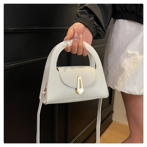 Detail of white PU leather handbag featuring a vintage gold trapezoidal magnetic buckle