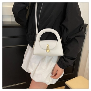 Close-up of white minimalist crossbody bag featuring golden trapezoid lock and curved handle