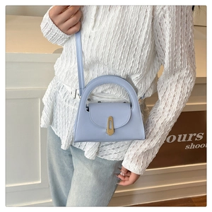 Close-up of light blue mini trapezoid handbag with gold metal lock on a model