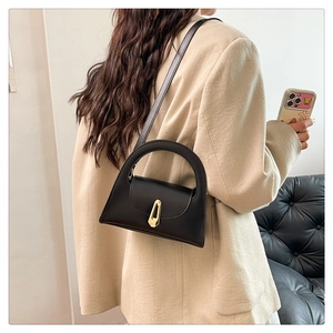 Minimalist black matte leather trapezoid handbag with gold lock and shoulder strap