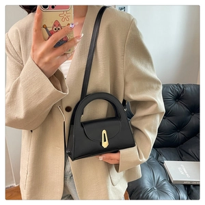 Detail of minimalist black semi-circle handbag with golden buckle worn by a model