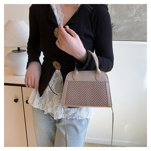 Detail of khaki herringbone woven crossbody bag with leather handles and fashion logo