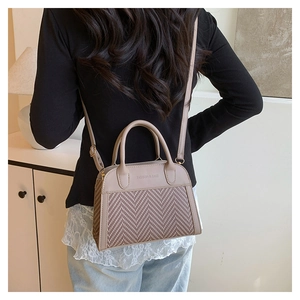 Detailed view of bicolor leather and woven handbag styled with casual outfit