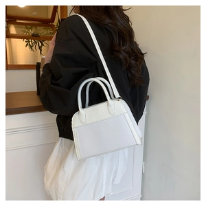 Modern white shell handbag with woven texture and adjustable shoulder strap shown on model