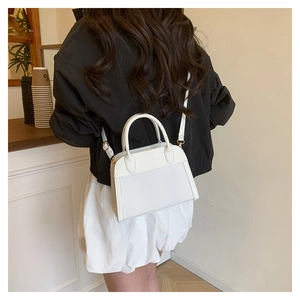 Detailed view of white contrasting handbag with textured panels and adjustable strap