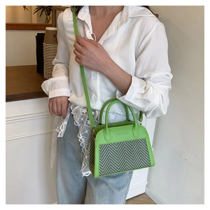 Dettaglio della borsa tote verde brillante con trama a spina di pesce e logo goffrato