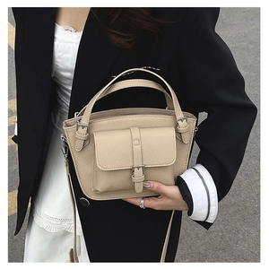 Detailed macro view of beige lychee texture leather bucket bag with front pocket flap