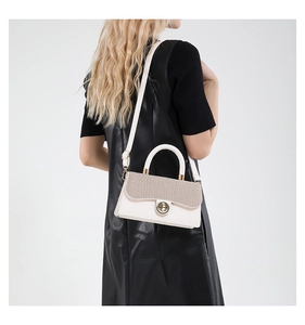 Detail of white leather handbag with woven flap, metal ring lock, and crossbody strap