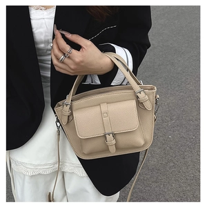 Close-up of beige lychee grain leather bucket bag with metallic buckle detail