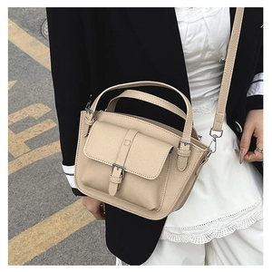 Detail of beige lychee leather bucket bag with silver buckle and crossbody strap
