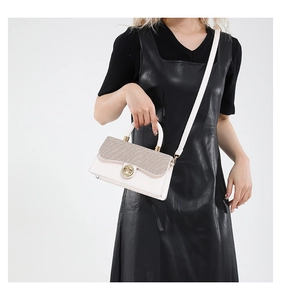 Detail of white and gold contrast stitching on a handbag with round metal buckle and strap