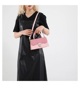 Detail of pink crossbody bag with textured flap and golden circular metal clasp closure