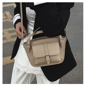 Close-up of beige lychee textured bucket bag featuring a decorative buckle pocket detail